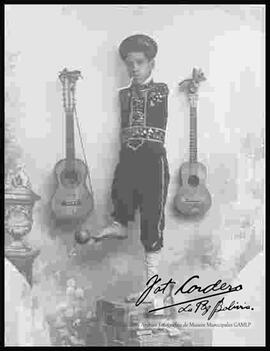 Foto de estudio del niño fenómeno junto a dos guitarras.