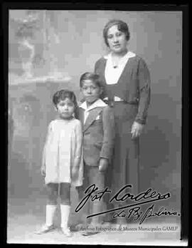 Foto de estudio de una madre, parada junto a sus dos hijos