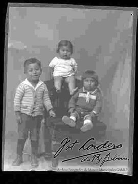 Foto de estudio de tres niños. Dos niños y una niña pequeña en un sillón
