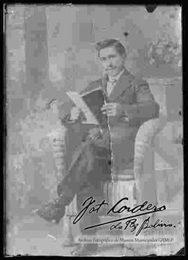 Reproducción de la imagen de un varón que se encuentra sentado en una silla de mimbre y leyendo un libro