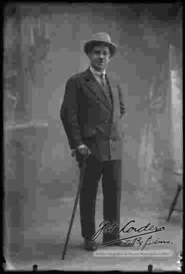 Foto de estudio de un varón vestido de traje, sombrero y bastón.