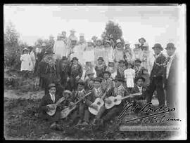 Familia y amigos en un día de campo celebrando carnavales, con un conjunto musical de estudiantina.