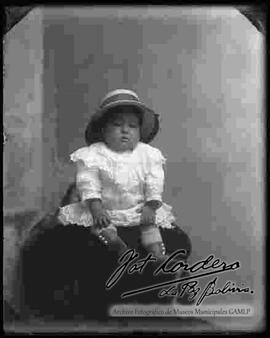 Foto de estudio de una niña pequeña que se encuentra sentada encima de un sillón