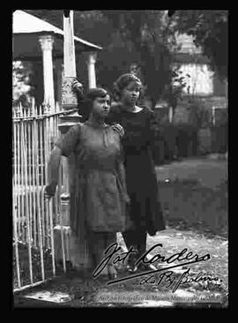 Dos señoritas paradas delante del kiosco de una plaza