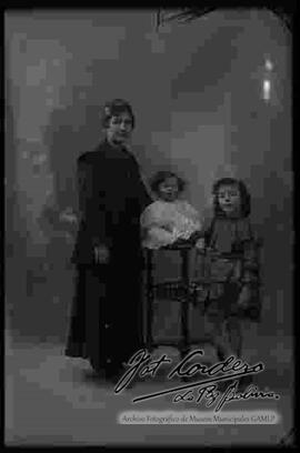 Foto de estudio de una familia. Una madre junto a sus dos hijas pequeñas