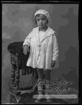 Foto de estudio de una niña parada encima de un sillón
