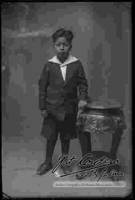 Foto de estudio de un niño junto a una mesita