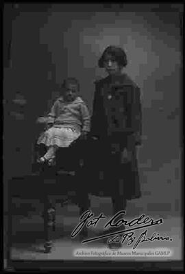 Foto de estudio de una joven junto a una niña que se encuentra sentada en la cabecera de un sillón