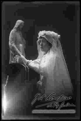 Foto de estudio de una niña  junto a una imagen religiosa, el día de su primera comunión