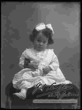 Foto de estudio de una niña pequeña, sentada encima de un sillón