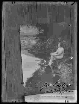 Reproducción de la la imagen de una mujer desnuda, sentada a orillas de un río.
