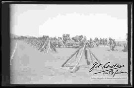 Tropas de soldados, descansando junto a pabellones de armas, en el campo de práctica de maniobras