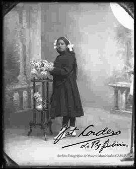 Foto de estudio de una joven parada junto a una mesita con flores