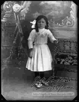 Foto de estudio de una niña parada junto a una silla