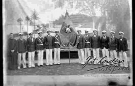 Grupo de estudiantes bachilleres del colegio San Calixto parados, agarrando el estandarte, con el fondo de un paisaje