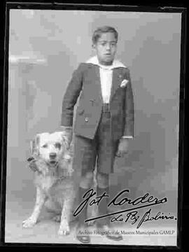 Foto de estudio de un niño parado a lado de su perro