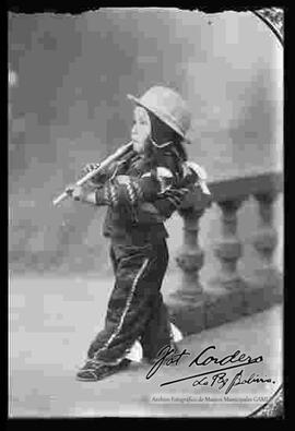 Foto de estudio. Un niño disfrazado de campesinito tocando su pinquillo.