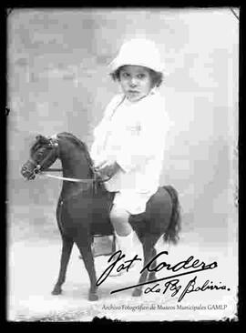 Foto de estudio de una niña montada en un caballito de juguete