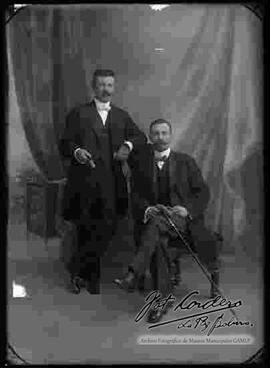 Foto de estudio de dos varones con un modelo de bigotes.