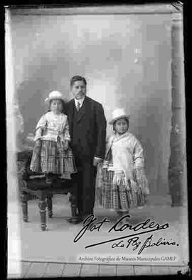 Foto de estudio de un padre junto a sus dos hijas vestidas de cholitas