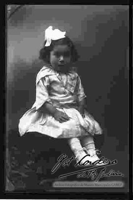 Foto de estudio de una niña pequeña sentada en la cabecera de un sillón