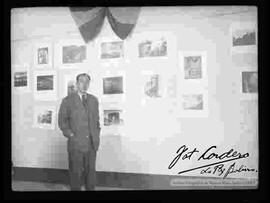 Julio Cordero Ordoñez, posando delante de las fotografías de exposición "Foto Cordero Jiménez", en el salón de la cancillería. octubre de 1948.