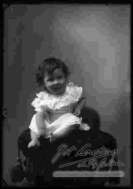 Foto de estudio de una niña pequeña, sentada encima de un sillón