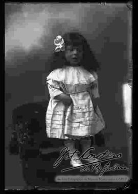 Foto de estudio de una niña pequeña que se encuentra parada encima de un sillón